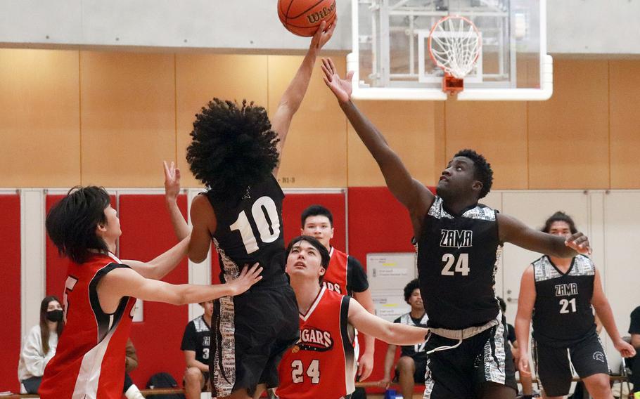 Zama's Christopher Jones snags a rebound over St. Maur defenders during Wednesday's Kanto Plain boys basketball game. The Trojans beat the Cougars 77-22.