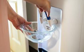 Richelle Dietz fills up a bowl of water from the water dispensary at her home on Monday, April 22, 2024, in Honolulu, Hawaii. The Dietz family relies on bi-weekly water deliveries for basic needs since their water was tainted in 2021.