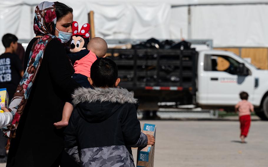 An Afghan family with new toys from the supply tent walk through an Afghan refugee camp on Nov. 4, 2021, in Holloman Air Force Base, New Mexico. 