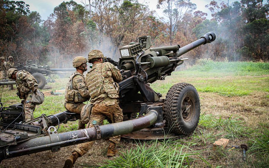 Soldiers fire artillery.