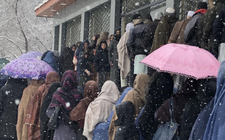 Afghan women wait in heavy snowfall for food donations from the World Food Program in Kabul, Afghanistan, on Jan. 4, 2022. 