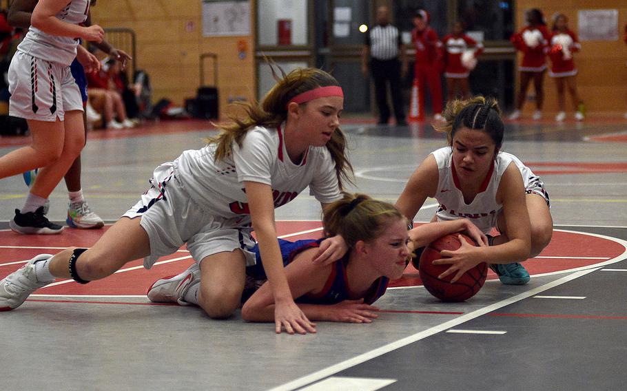 Kaiserslautern's Marisa Branch, right, and Ramstein's Charlotte Rhyne, center, drive after a ball during a Dec. 14, 2023, game at Kaiserslautern High School in Kaiserslautern, Germany. Also in the mix in Raider Ryann Phillips.