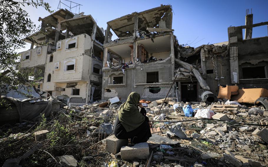 A displaced Palestinian woman looks at the ruins of a building hit in an Israeli airstrike this month. 