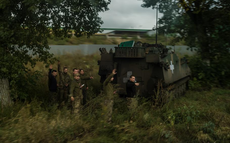 Ukrainian soldiers wave on the road between Balakliya and Kharkiv.