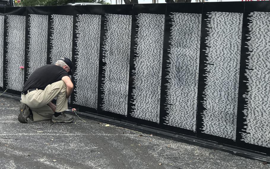 Herb Sennett, a West Palm Beach resident and U.S. Army veteran who served in Vietnam, bows in front of the section of the Vietnam Traveling Memorial Wall that bears the name of a buddy and fellow soldier. The exhibit is on display at the Hilton Palm Beach Airport through Sunday.