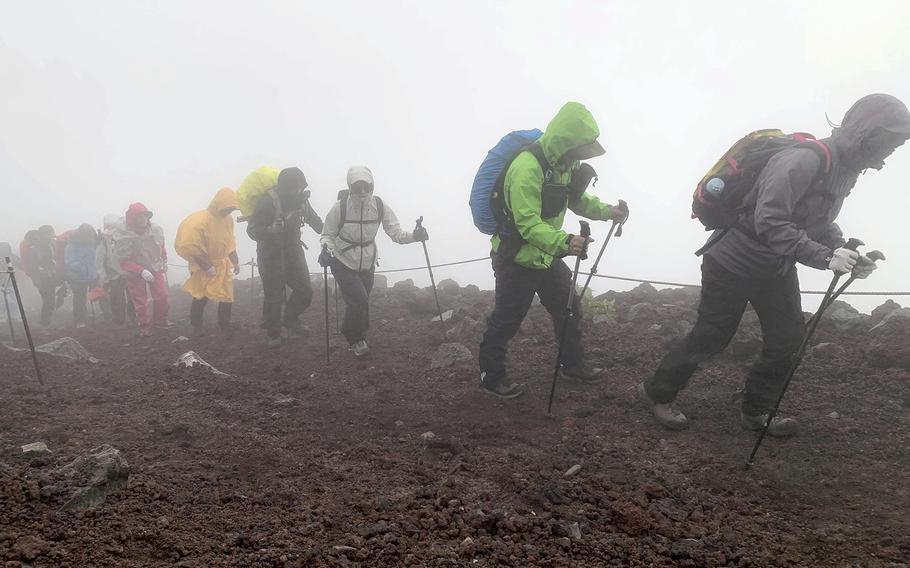 Climbers head to the summit of Mt. Fuji in bad weather.
