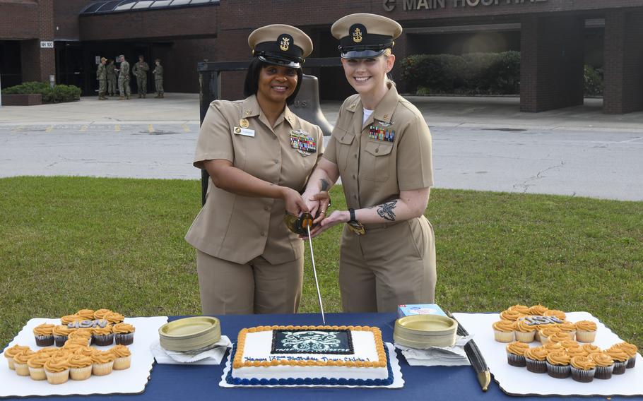 Two sailors cut a cake together