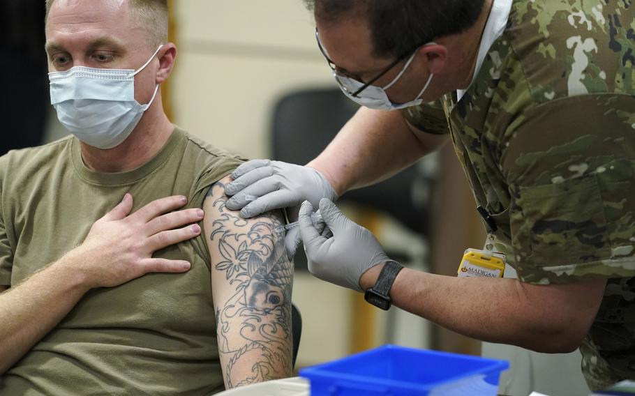 Staff Sgt. Travis Snyder, left, receives the first dose of the Pfizer COVID-19 vaccine.