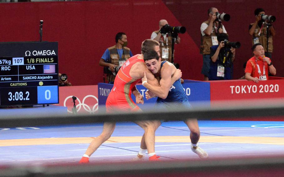 Army Spc. Alejandro Sancho, in blue, grapples with Russian Artem Surkov during their Olympic 67 kg Greco-Roman wrestling bout in Makuhari, Japan, Tuesday, Aug. 3, 2021.