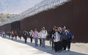 FILE - A group of people, including many from China, walk along the wall after crossing the border with Mexico to seek asylum, Oct. 24, 2023, near Jacumba, Calif. Beijing and Washington have quietly resumed cooperation on the deportation of Chinese immigrants who are in the U.S. illegally, as the two countries are reestablishing and widening contacts following their leaders' meeting in California late 2023. (AP Photo/Gregory Bull, File)
