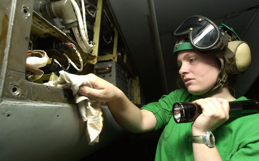 Petty Officer 3rd Class Rebecca Wood, assigned to VFA-154, cleans the inside of an avionics panel of an aircraft on the USS Kitty Hawk’s hangar bay Tuesday, April 16, 2002.