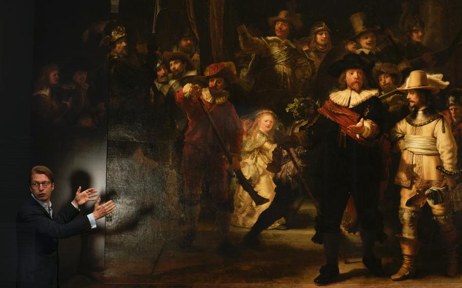 Museum director Taco Dibbits explains how Rembrandt's biggest painting the Night Watch just got bigger with the help of artificial intelligence in Amsterdam, Netherlands, Wednesday, June 23, 2021. Right above Dibbits, left, one of the added parts is seen, the Dutch national museum and art gallery reveals findings from a long-term project to examine in minute detail Rembrandt van Rijn's masterpiece the Night Watch.