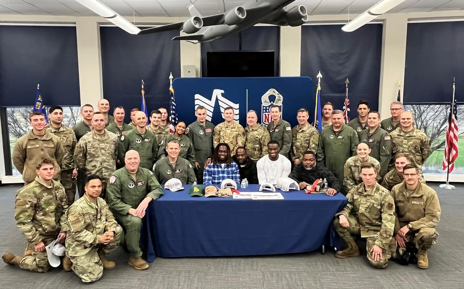 A group of airmen pose for a photo with football players and their dads