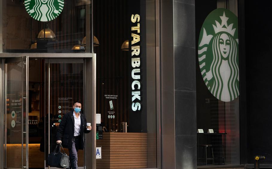A man carries a beverage as he walks out of a Starbucks coffee shop, Tuesday, Jan. 19, 2021, in New York.