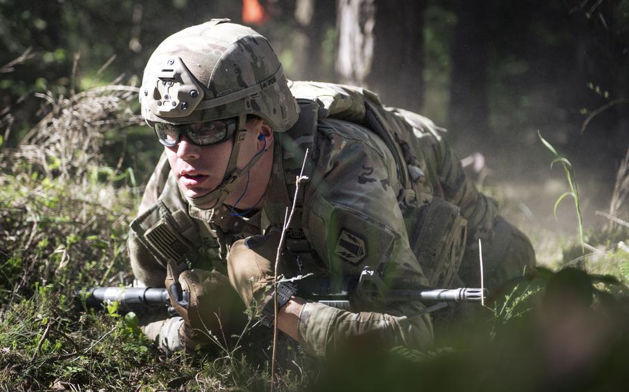 A soldier crawls through a forest/wood.