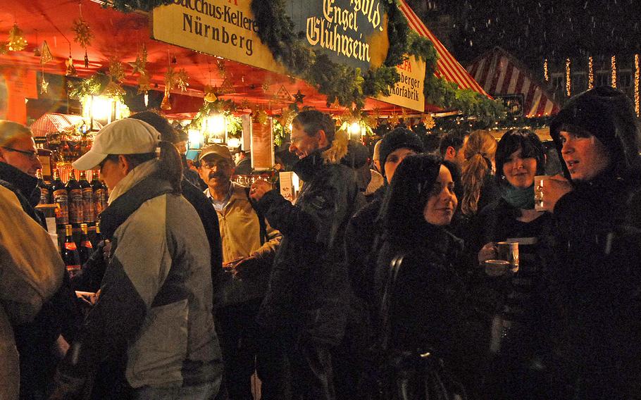 Visitors to the Nuremberg Christmas market warm themselves with gluehwein on a cold, wet December evening. The German state of Bavaria announced Nov. 19, 2021, that it is canceling all Christmas markets this year.