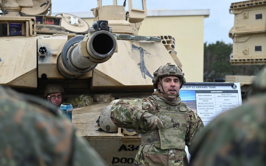 Sgt. 1st Class Arthur Sanchez, a tank commander with the U.S. Army's 1st Battalion, 37th Armored Regiment, discusses an M1A2 Abrams tank with German Army NCO School candidates  Feb. 22, 2024, during an exchange at U.S. Army Garrison Bavaria in Grafenwoehr, Germany.