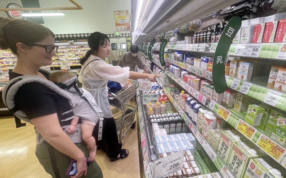 A member of the Japanese American Society shops with a Marine Corps spouse, who is carrying a baby, at a Japanese grocery store.