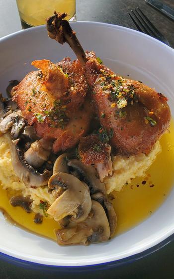 Confit chicken leg with creamy grits, roasted wild mushrooms, chili oil and herbs at The Stave Restaurant. 