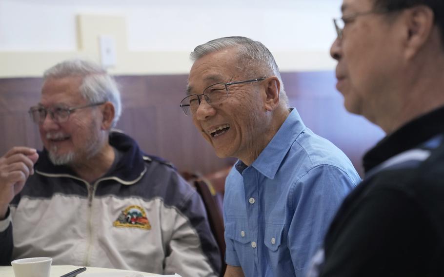 William Fong, middle, laughs while having lunch with other men at a restaurant.
