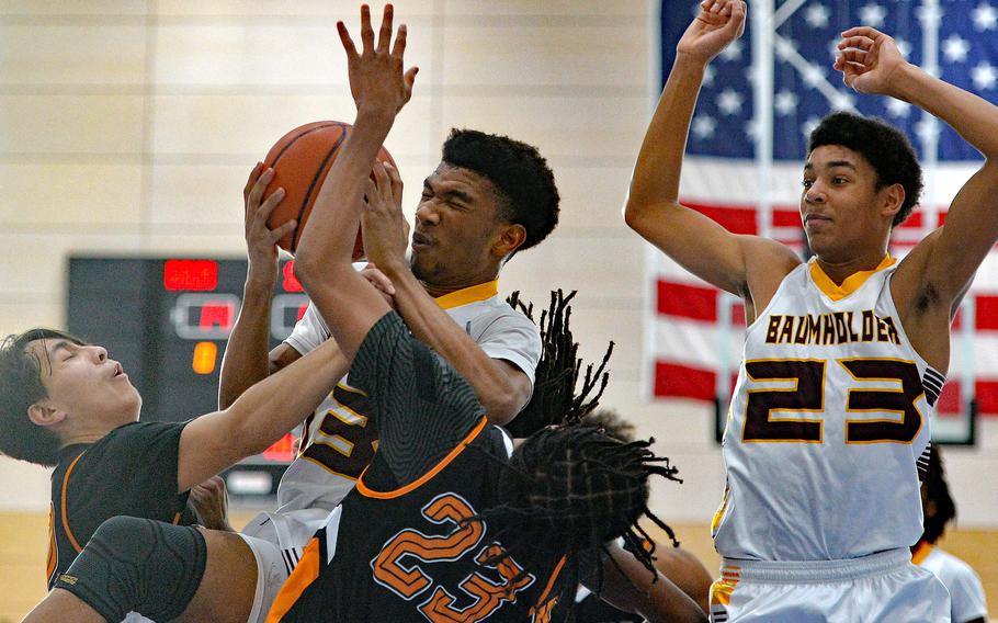 Caleb Piggé is fouled as he pulls down a rebound against Spangdahlem’s Casey Supinger, left, and Robert Leggett in the Division III championship game at the DODEA-Europe basketball finals in Ramstein, Germany, Feb. 18, 2023. Baumholder took the title with a 40-27 win. Damian Jung watches the action at right.