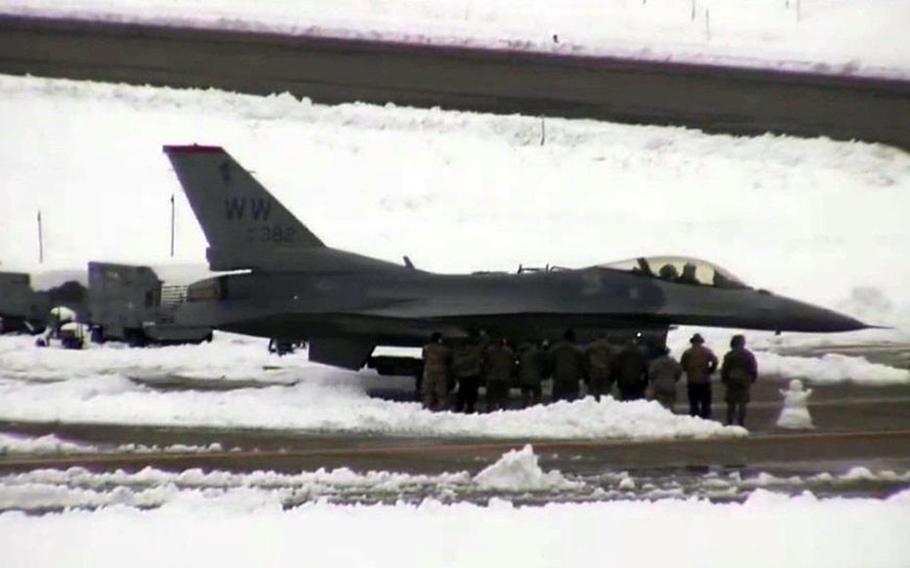 U.S. airmen stand next to an F-16 Fighting Falcon they repaired at Aomori Airport, Japan. The jet landed there last week because of an inflight emergency that forced the pilot to drop his external fuel tanks.