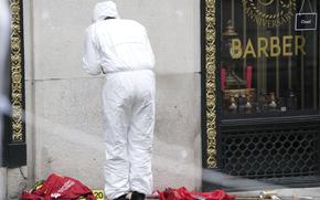 A Forensic officer looks at evidence near the site where a 53-year-old British man plowed a minivan into a crowd of Liverpool soccer fans who were celebrating the city's Premier League championship Monday, injuring more than 45 people in Liverpool, England, Tuesday, May 27, 2025.(AP Photo/Jon Super)