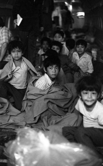 A black and white photo of children on a plane, some in blankets.