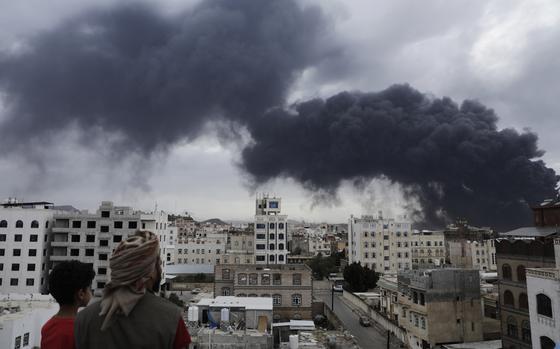 Yemenis watch as smoke billows following Israeli airstrikes targeting a power plant and Sanaa Airport.