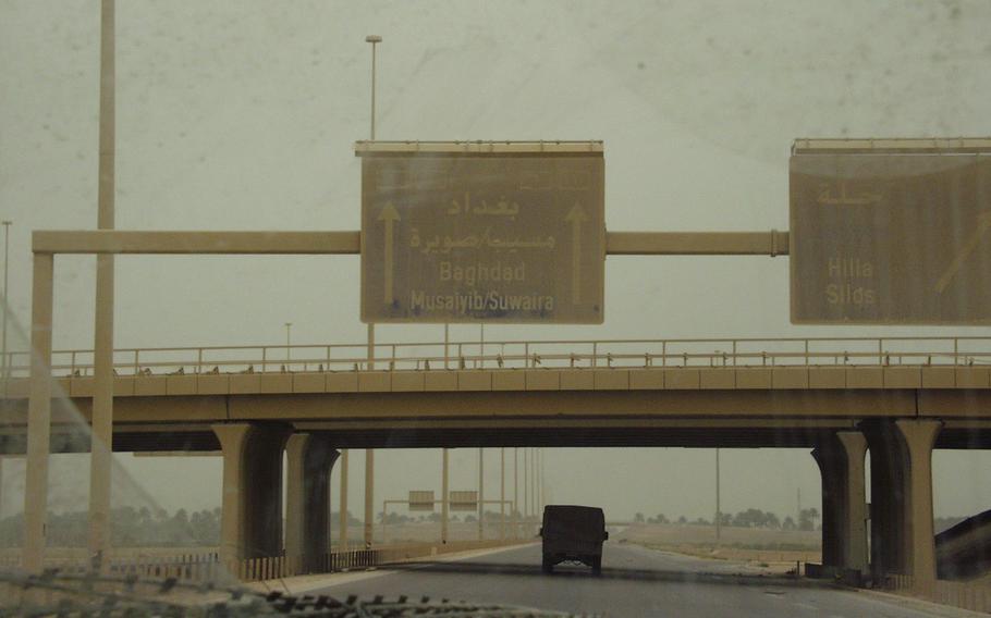 A highway overpass is seen with a sign indicating that Baghdad is ahead.