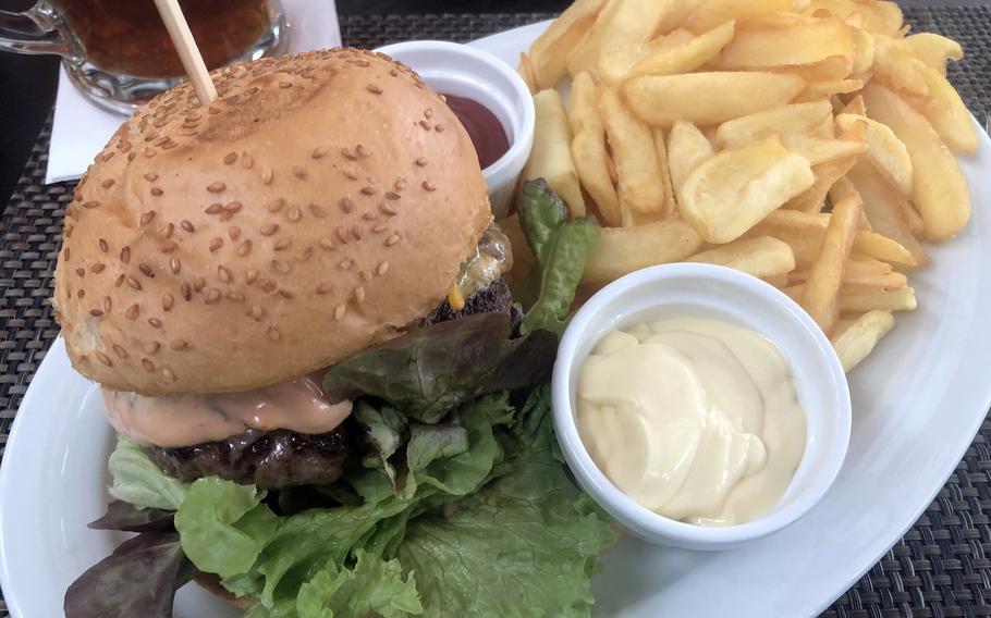 The Angus beef burger at Lumen in Wiesbaden, Germany, comes with fried onions, relish, lettuce, tomato, cheddar cheese and cocktail sauce, along with a portion of fries.