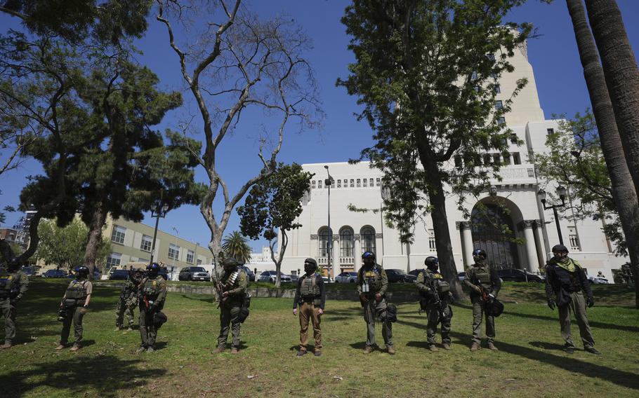 Federal agents standing in a park.