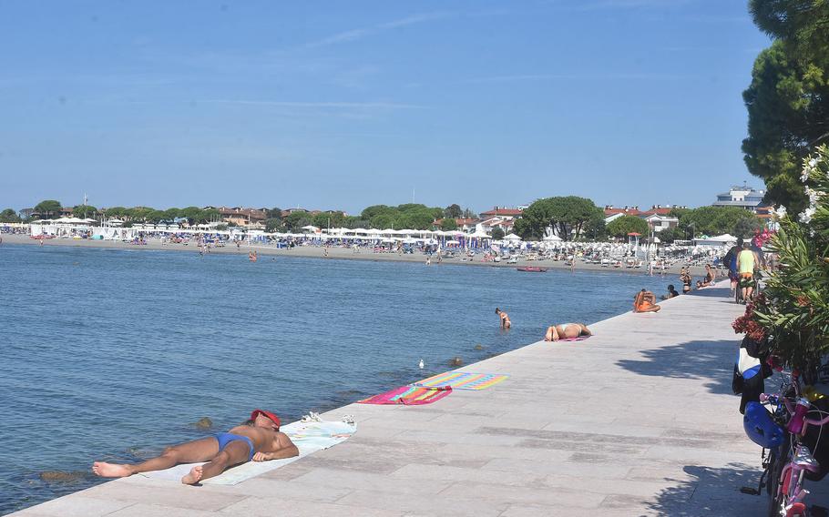 A large concrete barrier helps protect the Italian city of Grado from storm surges of the Adriatic Sea. But it also serves as a walkway between the city’s main beaches and a place for sunbathers to do their thing.