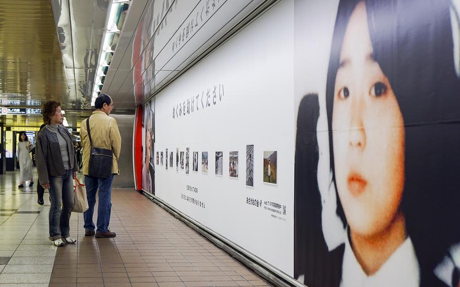 Commuters look at photos of Megumi Yokota, who was abducted by North Koreans in 1977, displayed at Shinjuku Station in Tokyo, May 9, 2018.