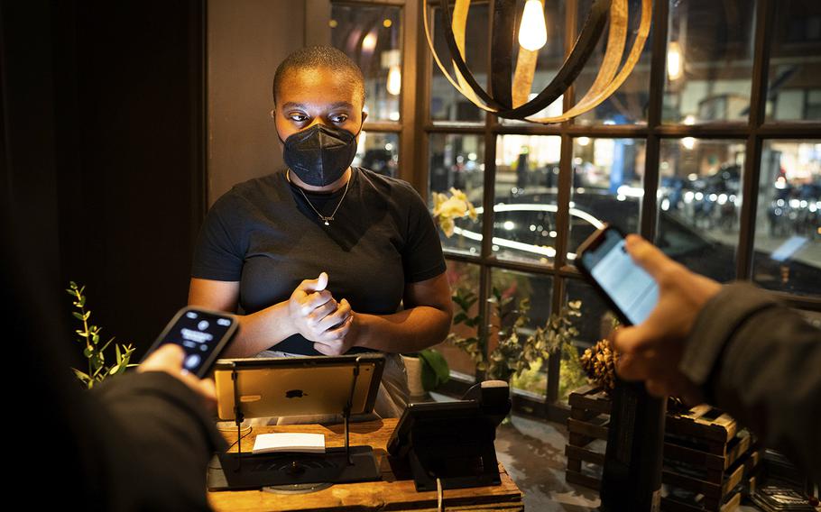 Hostess Khaliah Corley checks vaccination cards at a Philadelphia restaurant in February 2022. 