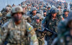 A large group of American and South Korean soldiers in camouflage combat gear march carrying machine guns.
