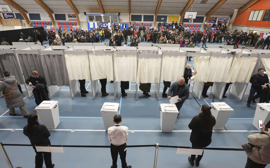 People lining up to vote in boths closed off by curtains.