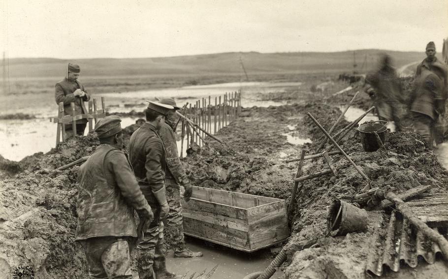 The Graves Registration Service removes bodies near Grandpre, Ardennes, France, for reburial. Much of the grisly work was done by African American soldiers in labor battalions. The men are wearing waders, and one has a mask. 