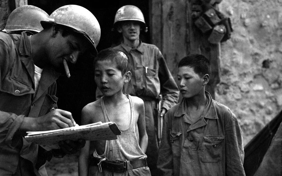 A U.S. soldier questions two boys serving in the North Korean army after their capture on Sept. 18, 1950.