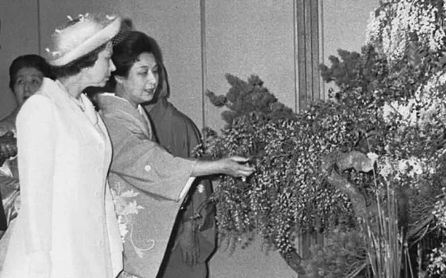 Queen Elizabeth II and Princess Takamatsu admire an Ikebana flower arrangement at the Japanese-style annex of the Akasaka Palace on May 8, 1975. The Queen and her husband, the Duke of Edinburgh, arrived in Tokyo May 7 for a six-day state visit. The royal couple stayed at the Akasaka Palace guest house. The visit was the first by a reigning monarch of Great Britain. 