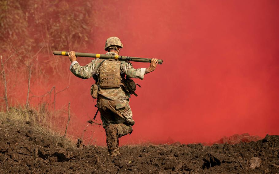 A U.S. soldier runs through red smoke carrying a Bangalore torpedo during a live-fire range at Baturaja Training Area, Indonesia, Aug. 12, 2021, during the Garuda Shield exercise.