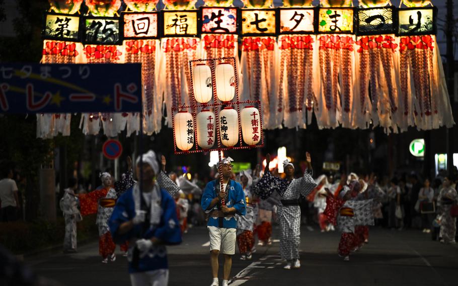 Folk dances with Japanese lanterns move through the streets.