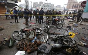 Police officials examine the site of a bomb explosion, in Lahore, Pakistan, Thursday, Jan. 20, 2022. Police said the powerful bomb exploded in a crowded bazar in Pakistan's second largest city of Lahore, killing several people and wounding dozens of others. (AP Photo/K.M. Chaudary)