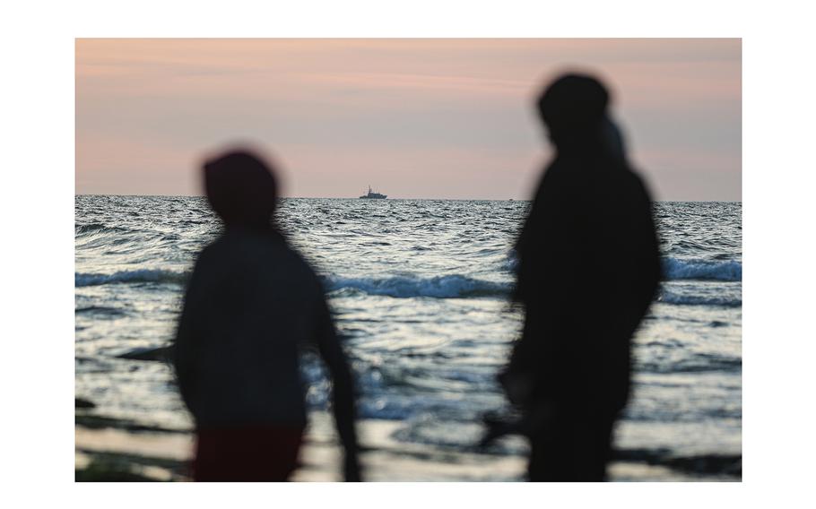 From a beach in southern Gaza, displaced Palestinians look out at an Israeli gunboat in February.