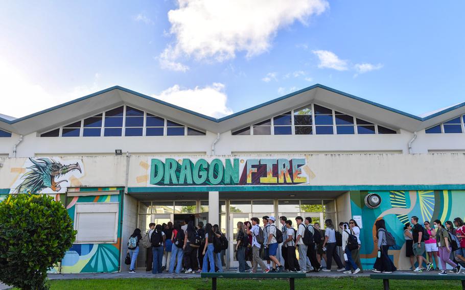 Students enter Kubasaki High School under a sign that reads “Dragon Fire.”