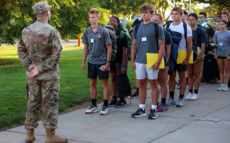 Cadets stand in lines in front of a uniformed soldier.