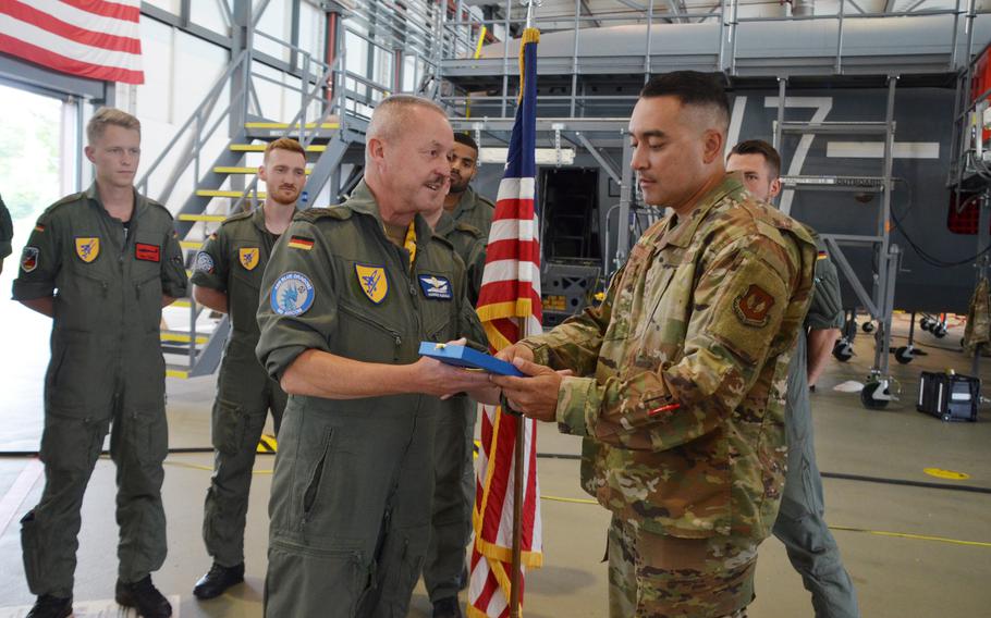 Col. Johannes Rudolf, foreground left, presents Senior Master Sgt. Dominik Gutierrez with a plaque for hosting seven cadets from Germany's University of the Armed Forces in Munich for two weeks of training at Ramstein Air Base, July 15, 2021. The aeronautical engineering students, who will go on to pilot training at Sheppard Air Force Base in Wichita Falls, Texas, are the first from the German military academy to do their required practical training with the U.S. Air Force at Ramstein Air Base.