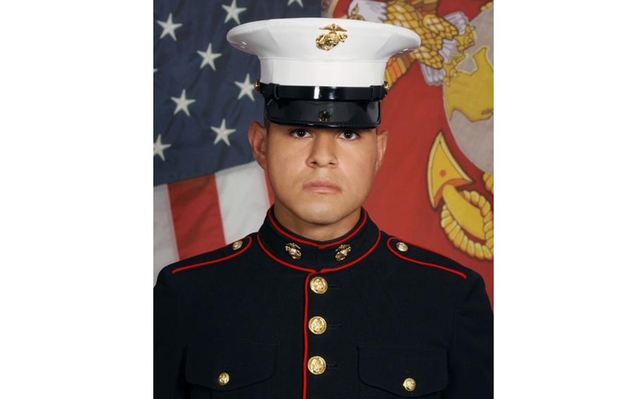 Portrait of a Marine in dress uniform and hat in front of U.S. and Marine flags.