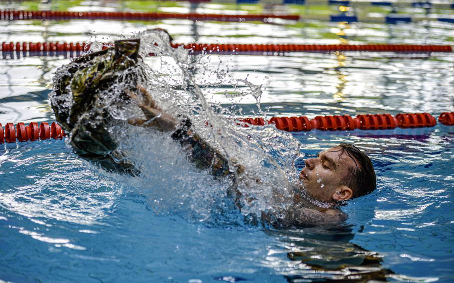 Air Force Master Sgt. Ross Kosakowski, serving as a temporary first sergeant with the 1st Air Combat Operations Squadron, throws his uniform top as he begins the swim portion of the German Armed Forces Badge for Military Proficiency at Ramstein Air Base, Germany, April 22, 2024.