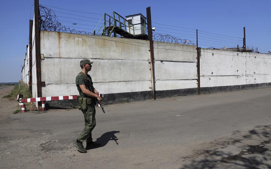 A soldier stands guard next to a wall of a prison in Olenivka, in an area controlled by Russian-backed separatist forces, eastern Ukraine, July 29, 2022. A Russian news agency is reporting that the country is preparing to send a battalion of Ukrainian prisoners of war to the front lines in their homeland to fight on Moscow’s side in the war. The Associated Press could not immediately confirm the authenticity of the report or if the POWs were coerced.